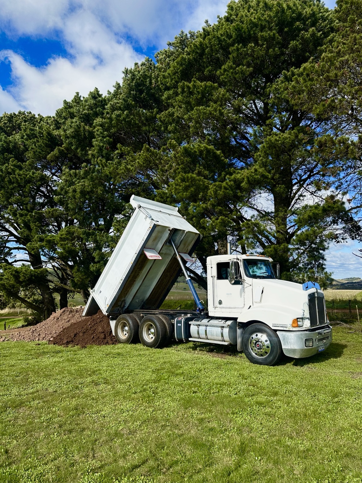 White tipper unloading material on a rural site